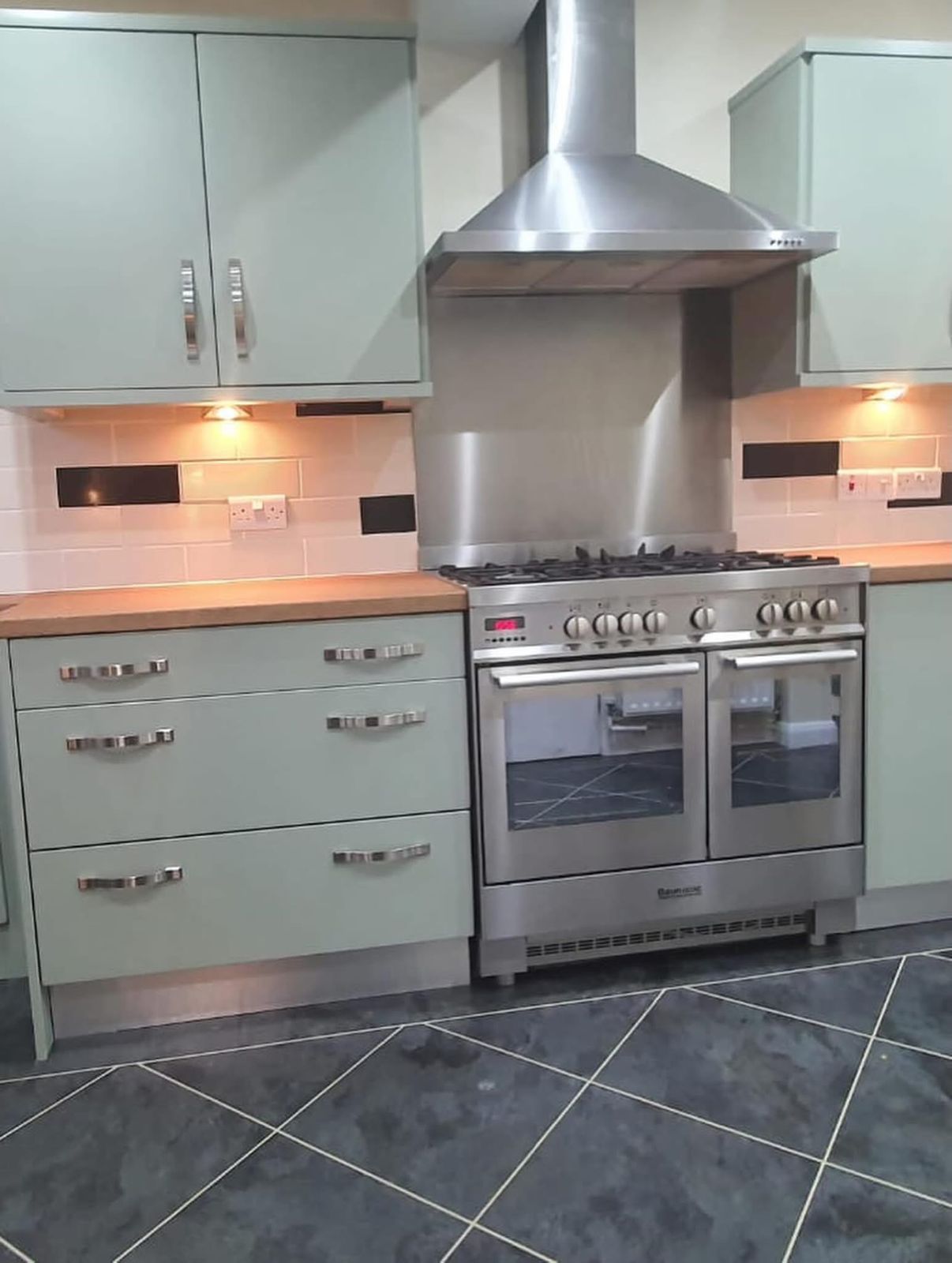 Sage green kitchen drawers and range cooker after vinyl wrap