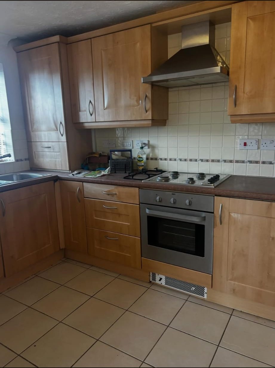 Oak kitchen cabinets around the hob and extractor before vinyl wrap
